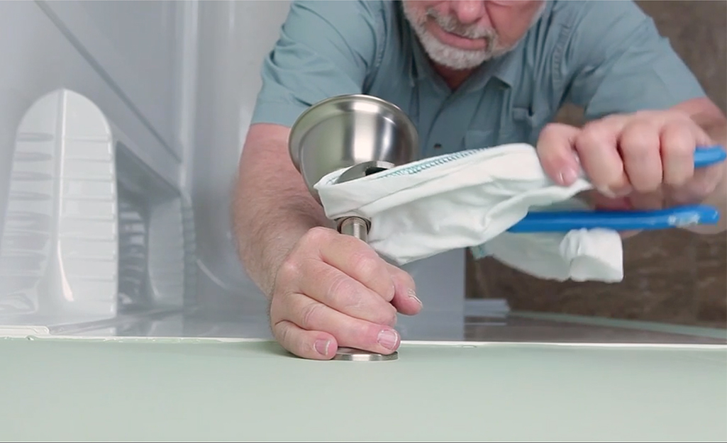 A man removing the old trim on his shower faucet.