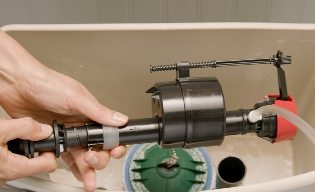 A person inserting a new fill valve.
