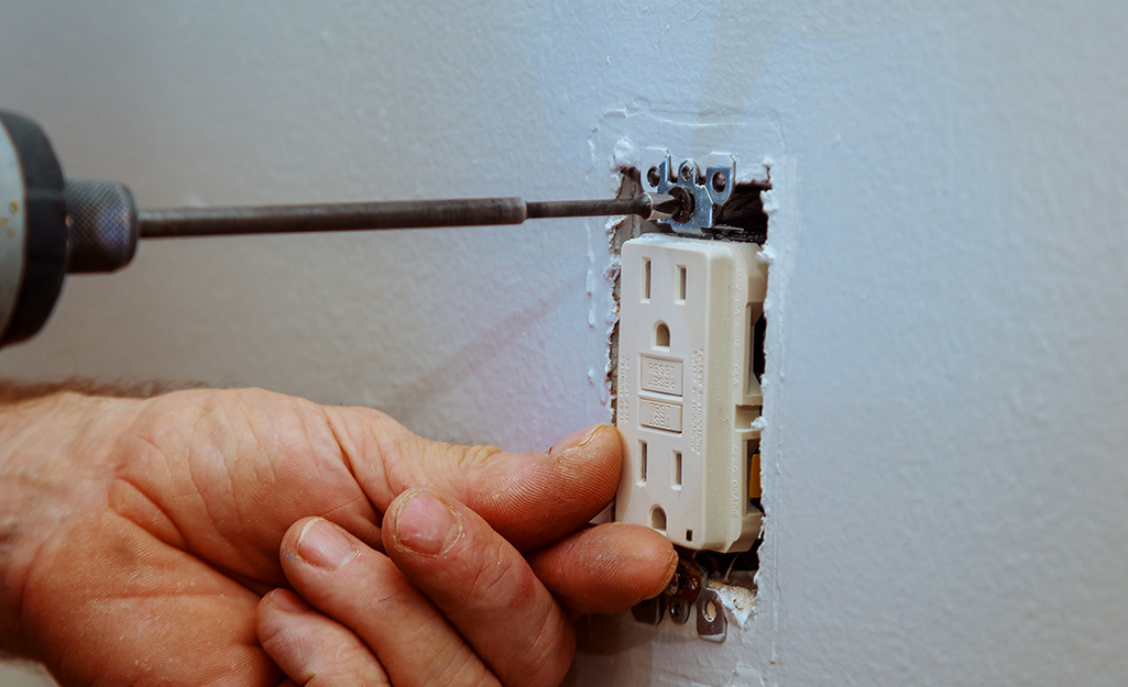 A person begins removing the outlet receptacle from the wall.