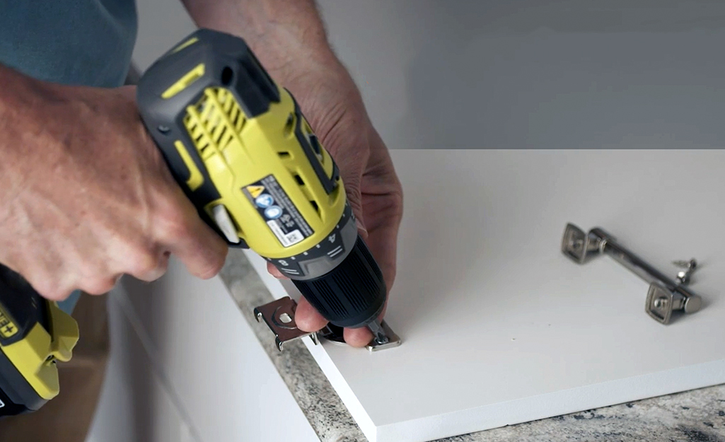 A person removing hardware from a cabinet door. A person removing hardware from a cabinet door.