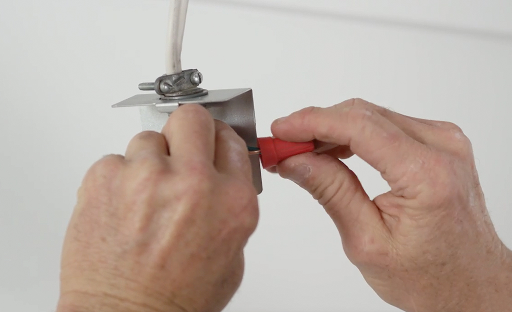 A person attaches electrical wiring during a bathroom exhaust fan installation. A person attaches electrical wiring during a bathroom exhaust fan installation.