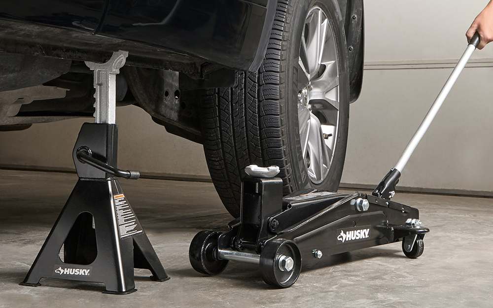A jack stand supporting a car by the frame as a floor jack is moved out of position. A jack stand supporting a car by the frame as a floor jack is moved out of position.