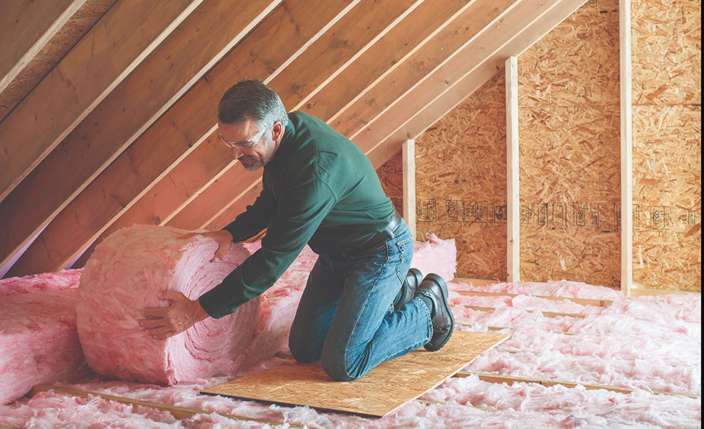 A man installs insulation in an attic.