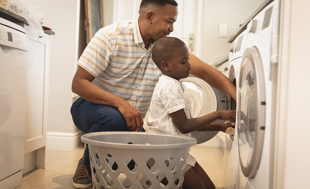 A father and son take laundry out of a dryer.