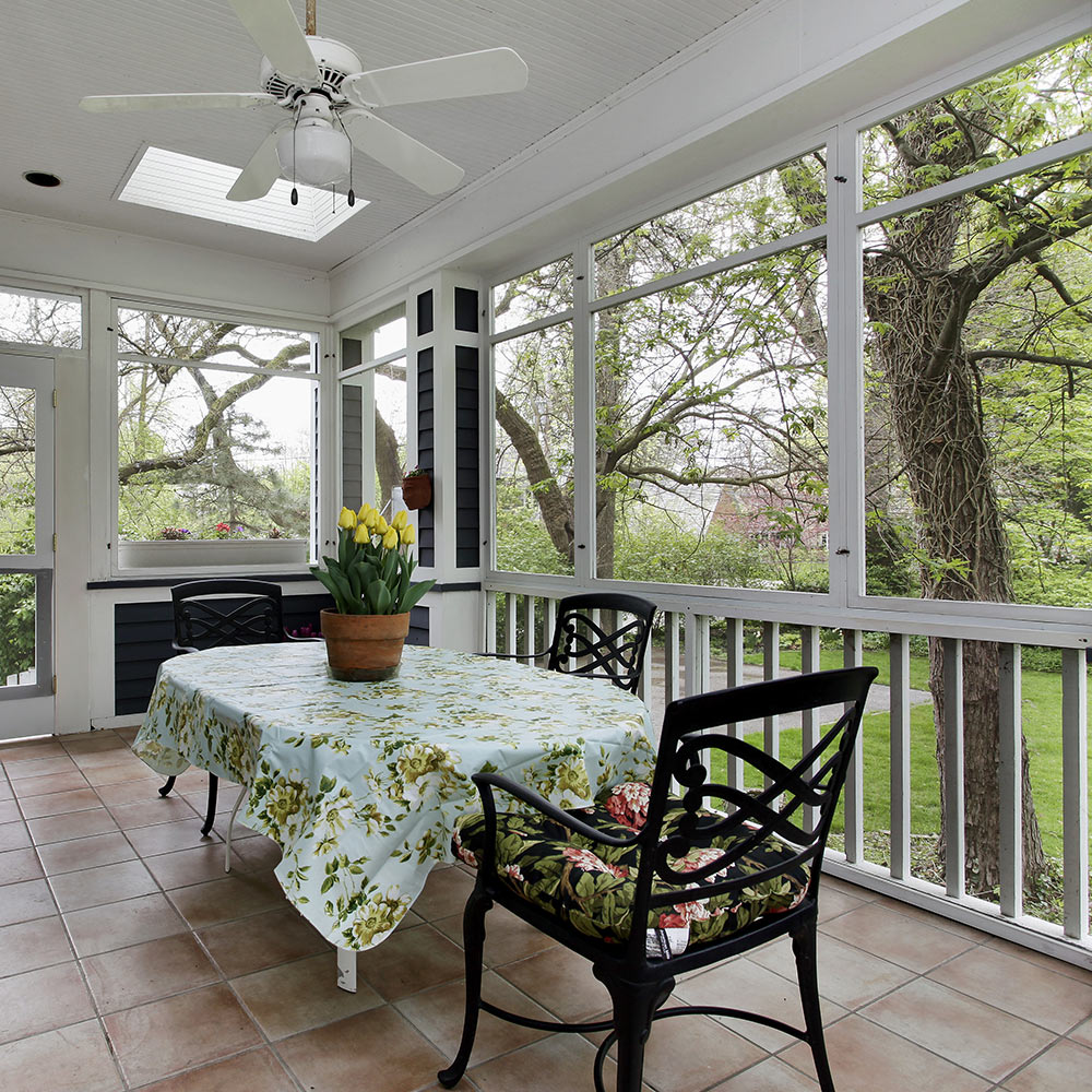 A screened-in porch surrounds a patio table with chairs.