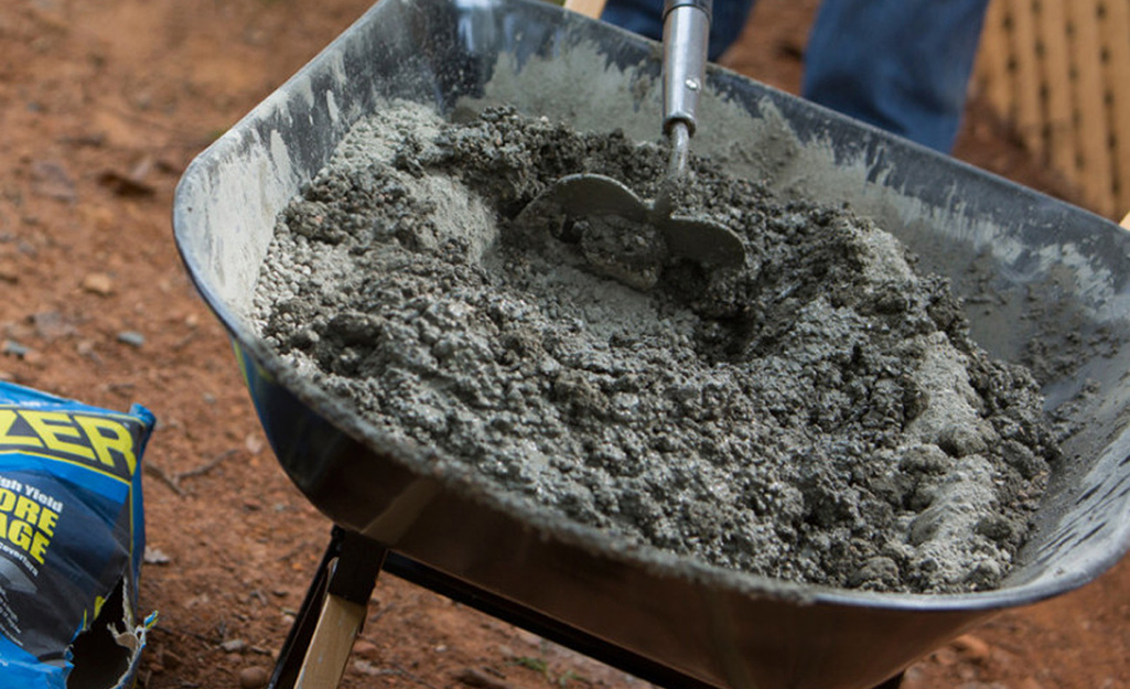 Concrete being mixed in a wheelbarrow.