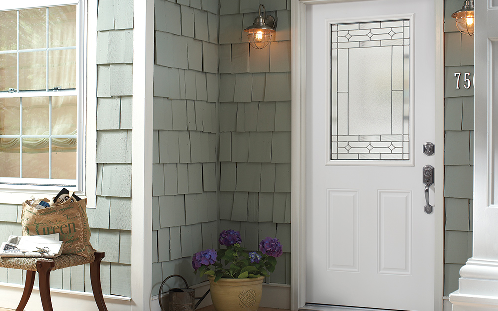 A white front door with a glass panel has a deadbolt lock for security.