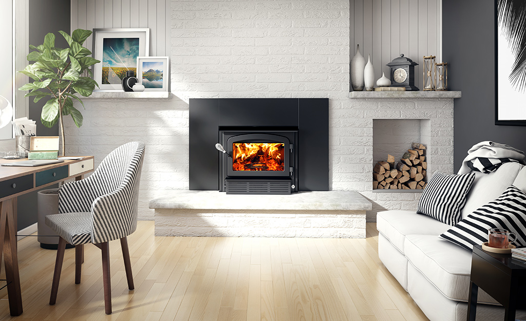 Logs burn in a black fireplace insert in a living room.