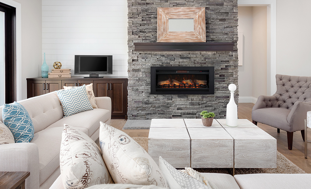 A fire glows in a black fireplace insert in a living room.