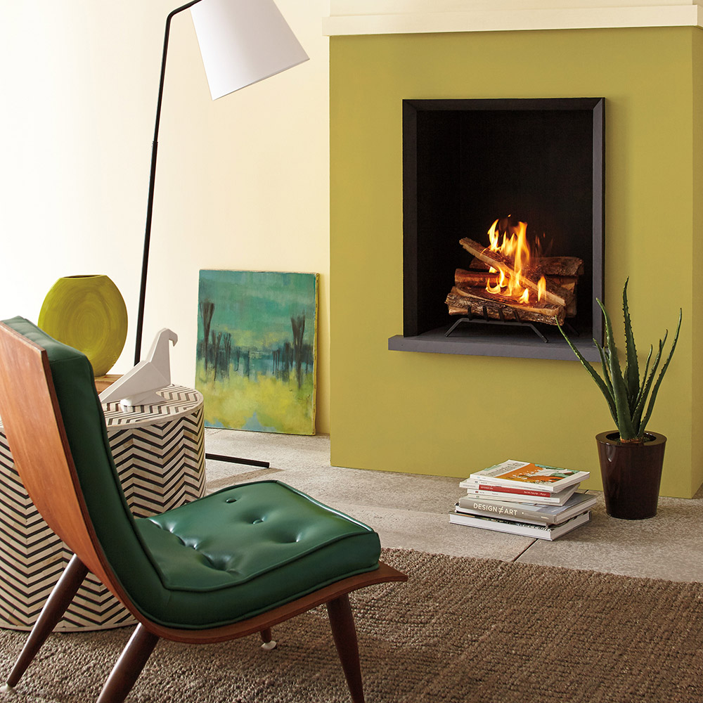 A green leather lounge chair sits in view of a wall-mounted fireplace.