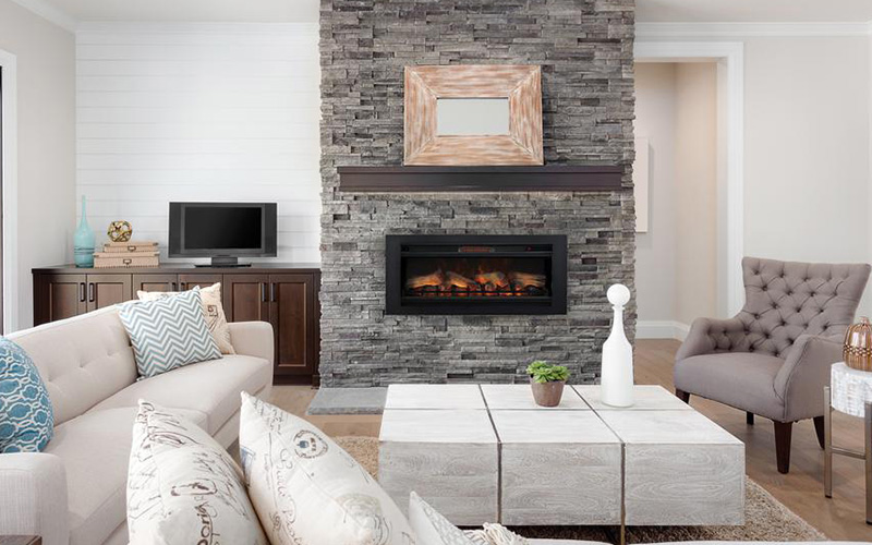 A gray stone wall serves as the backdrop for a fireplace insert in a living room.