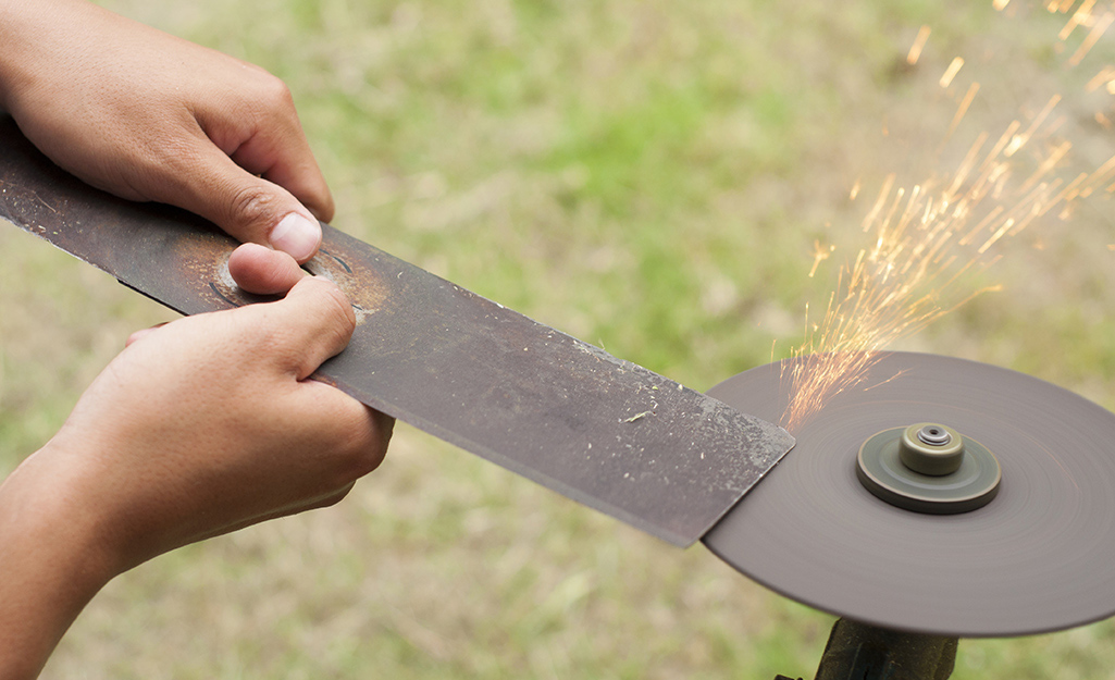 A person sharpening a lawn mower blade.