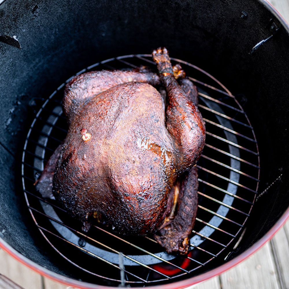 A turkey being cooked on a smoker.