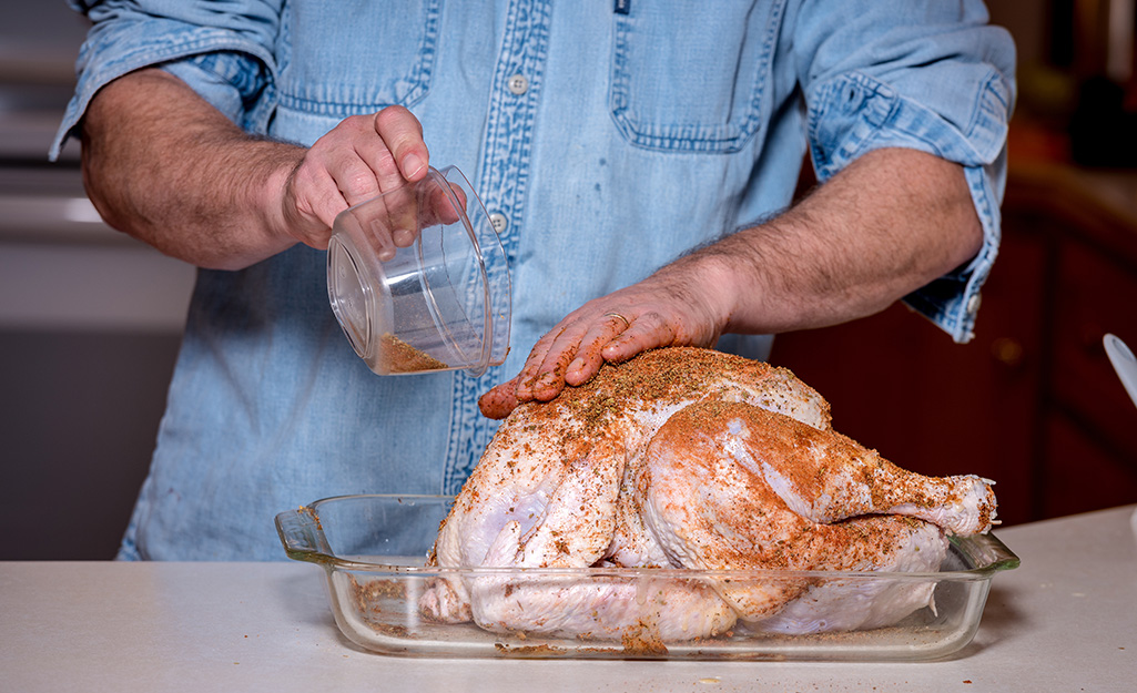 A man prepping his turkey to be smoked.