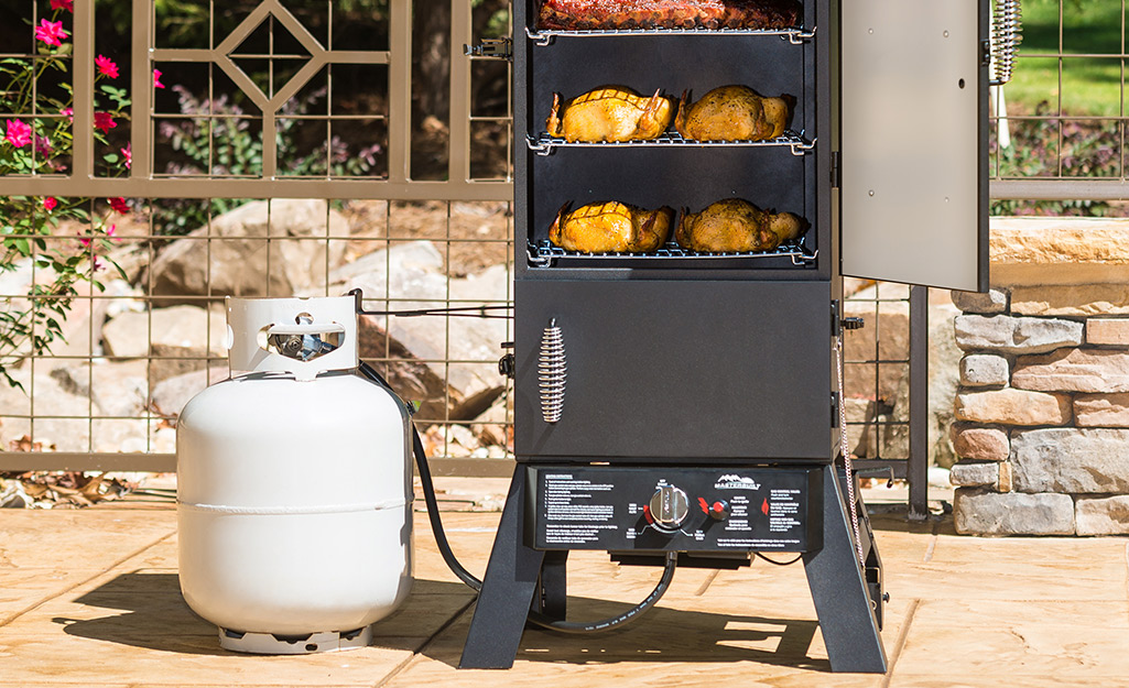 A smoker with multiple meats on it. 