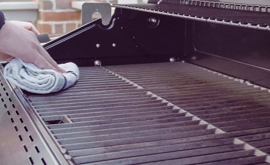 A person cleaning a grill top.