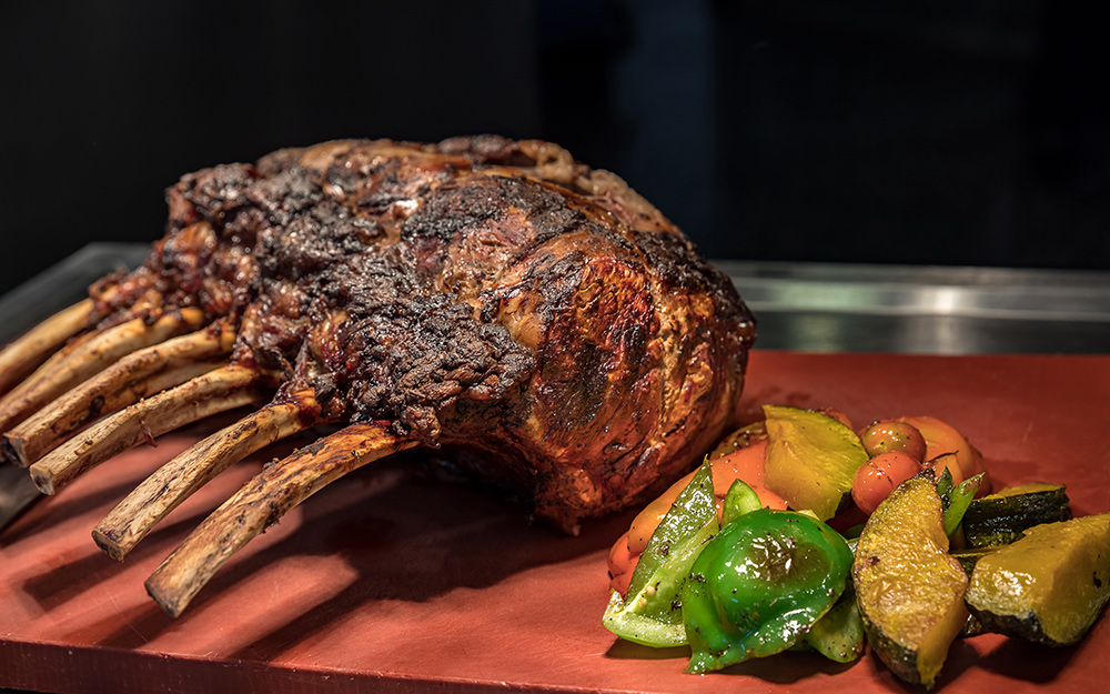 Smoked prime rib sits on a tray next to smoked vegetables. Smoked prime rib sits on a tray next to smoked vegetables.