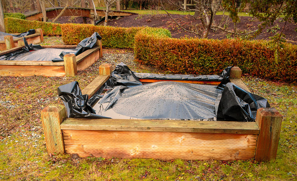 Plastic covering resting soil in raised garden beds.
