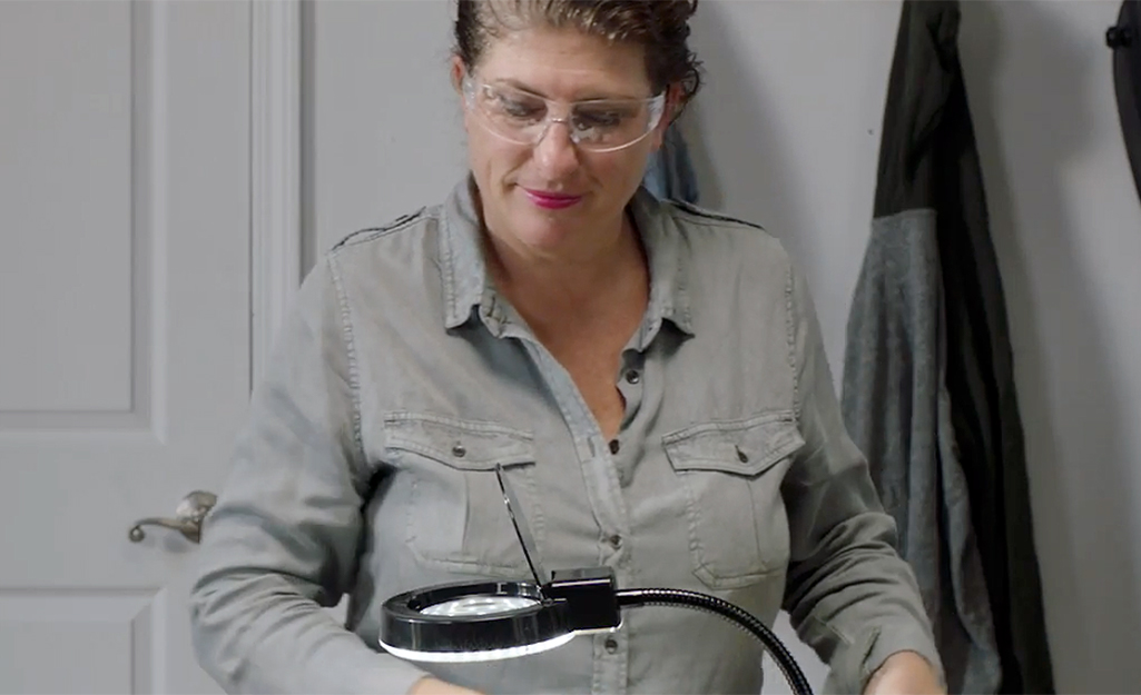 A woman wears safety goggles to solder jewelry.