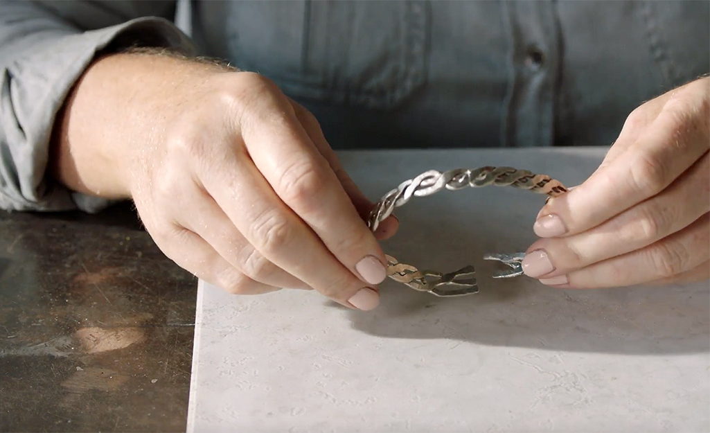 A person pulls on a bracelet to check the bond after soldering.