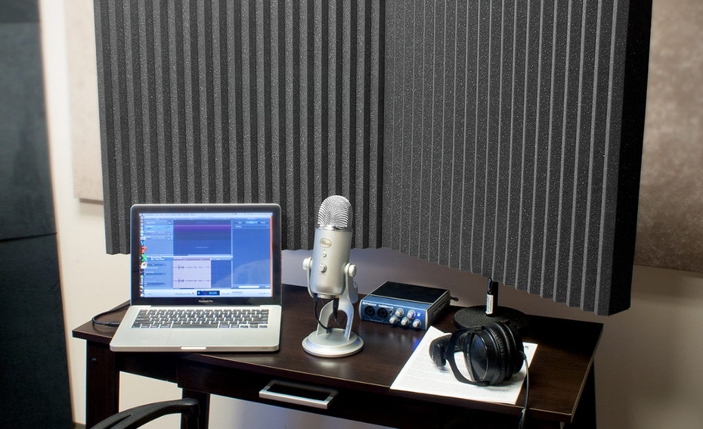 A simple home recording studio has soundproofing panels along the wall.