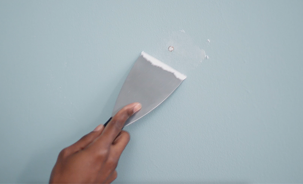 A person patching a hole in the wall before painting. 