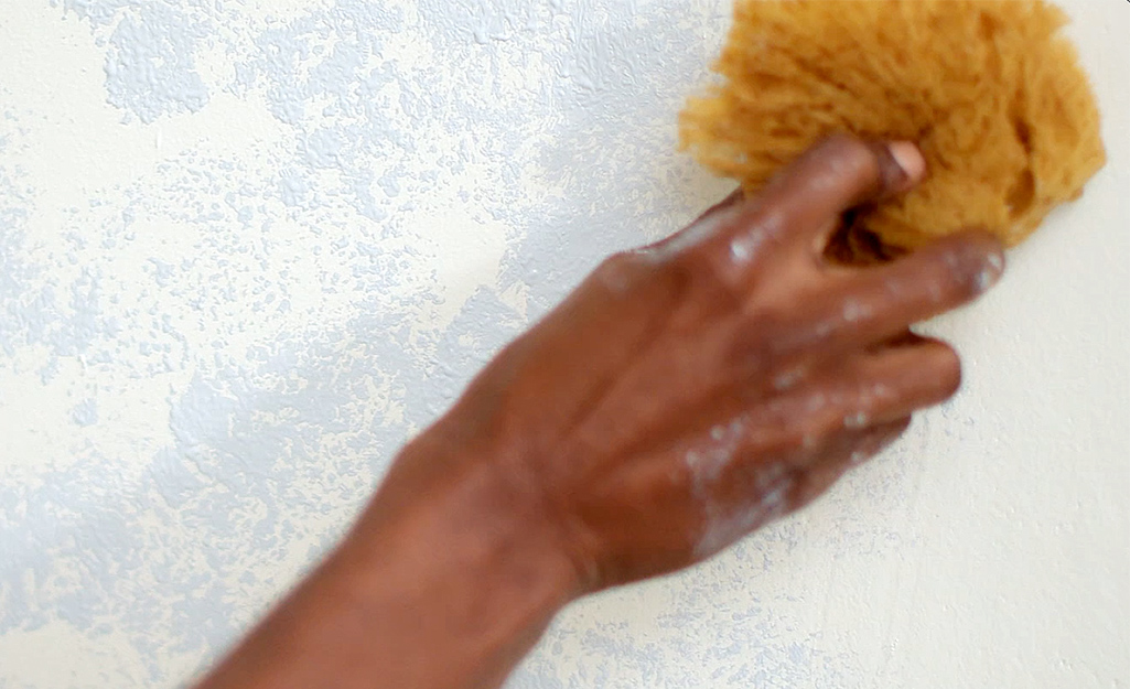 A person applying glaze to a wall.