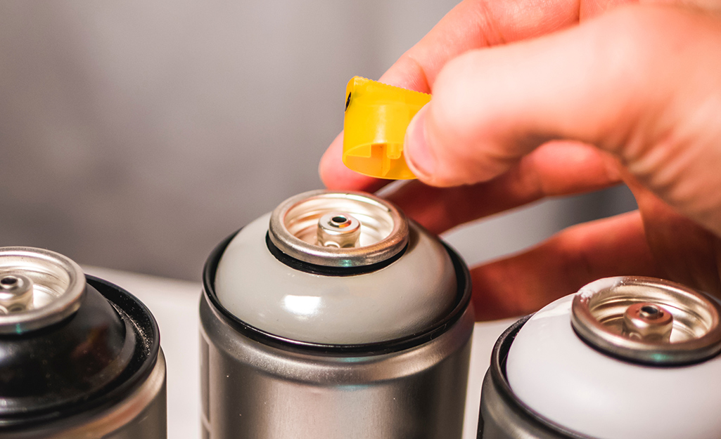 A person removing the nozzle from a can of spray paint.