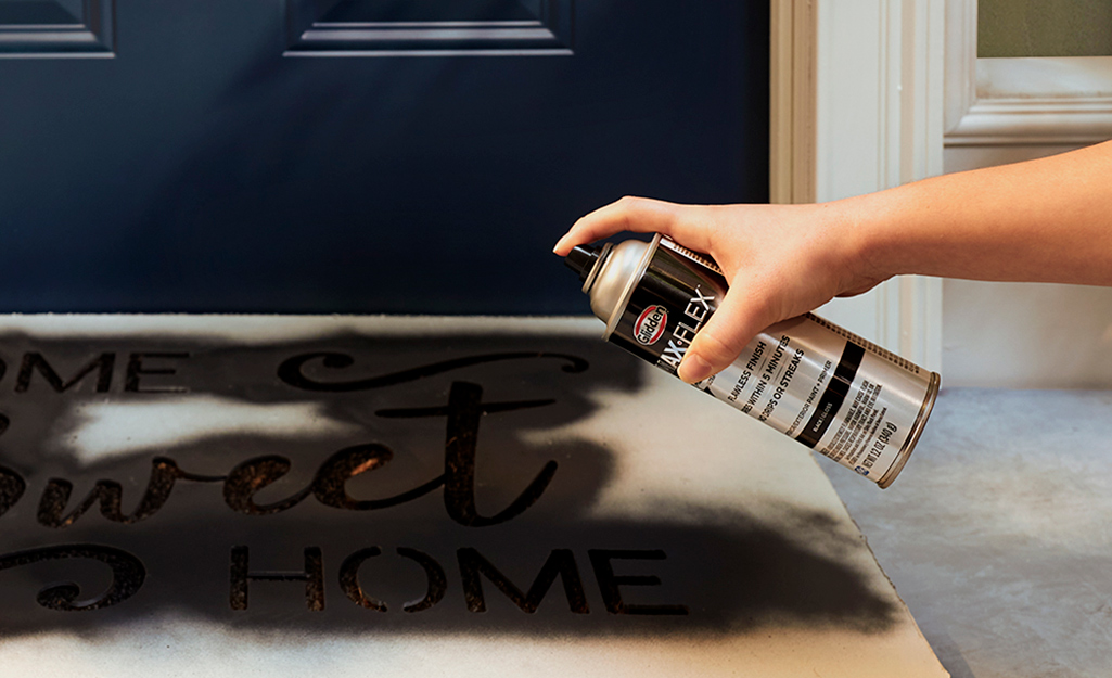 A person spray painting a doormat.