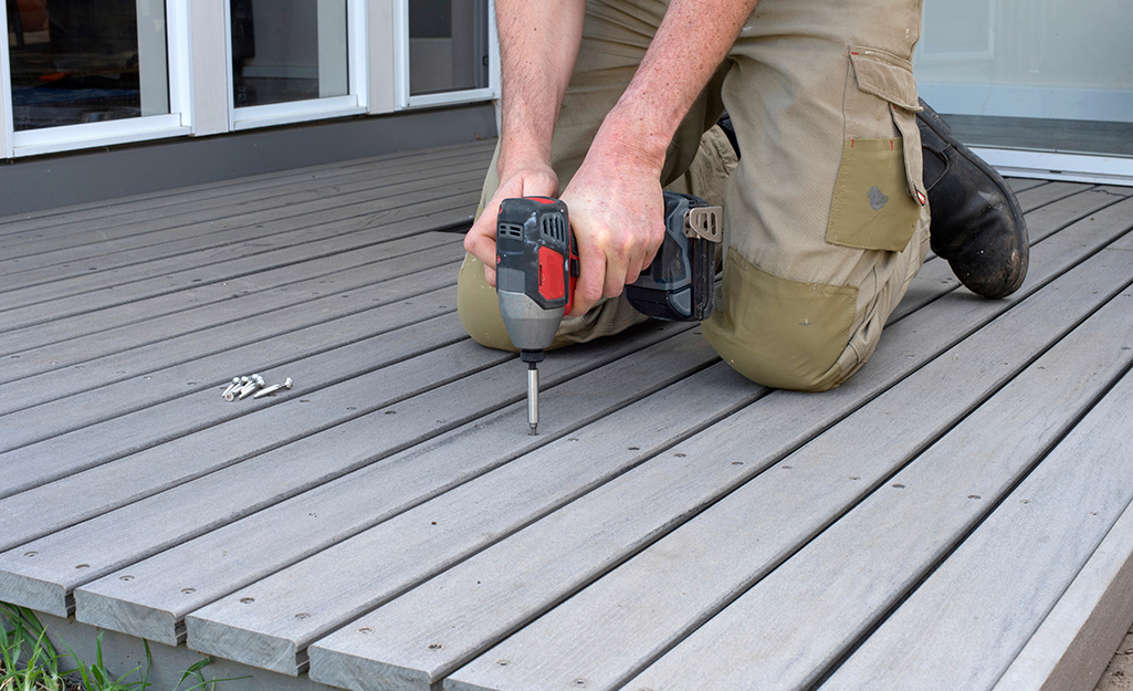 A person uses a powder drill to repair a deck