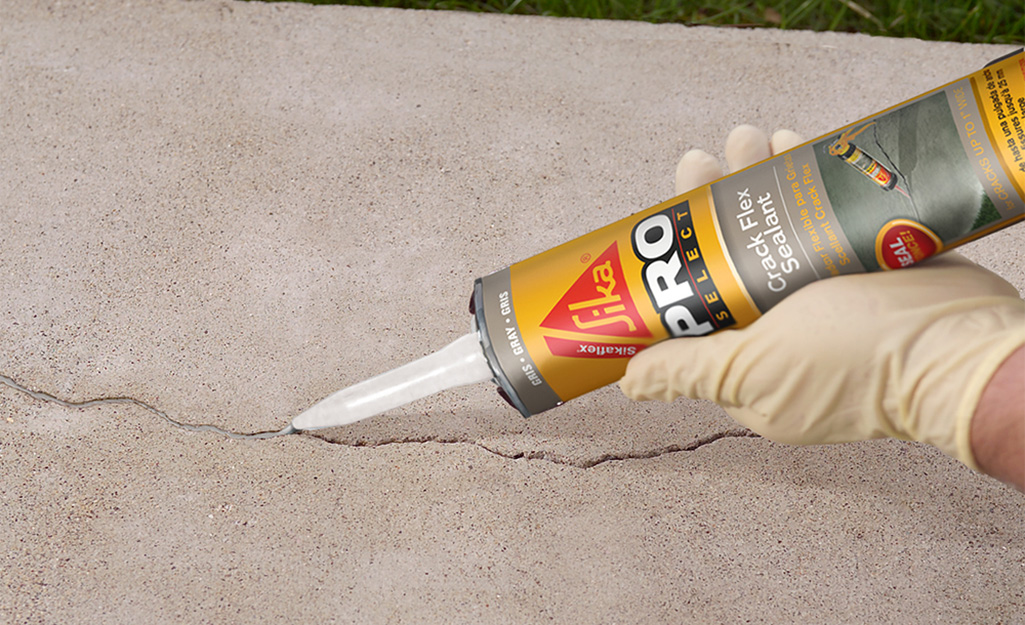 A person applying sealant to a crack in concrete.