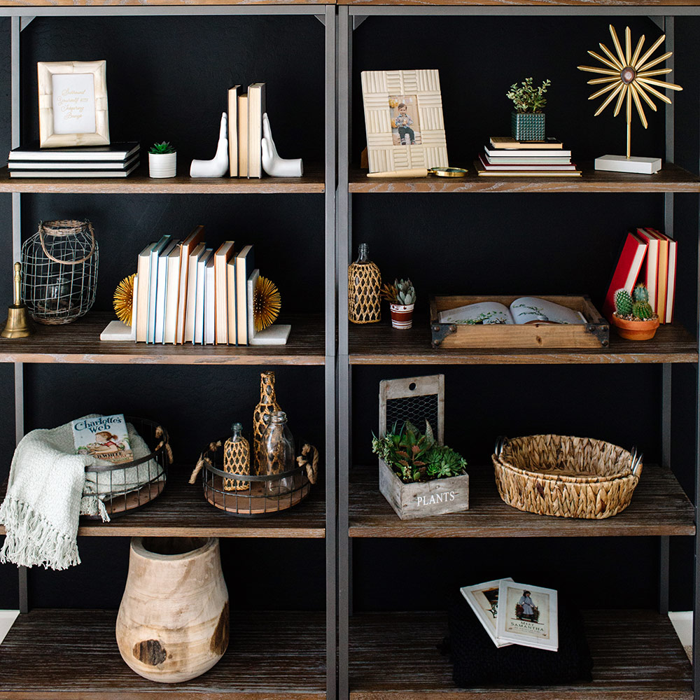 Two industrial style open bookcases styled with a variety of books and decor.