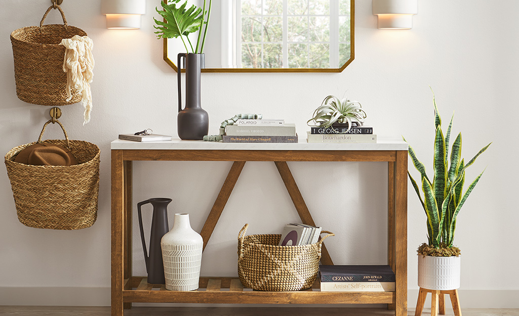 A two-tier console table in the entry with storage baskets and a gold mirror