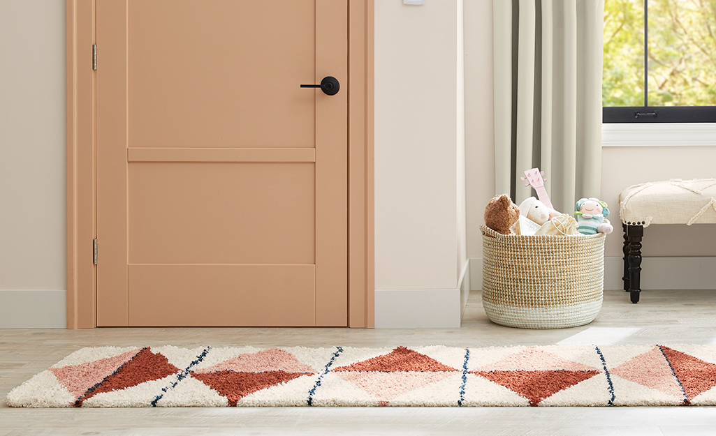 A salmon painted interior door with a geo print runner rug in the foyer