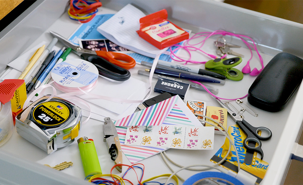 A messy drawer holds glasses, scissors and more.