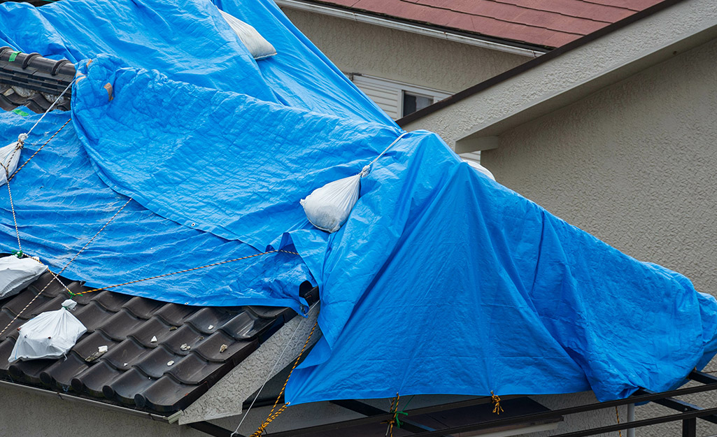 A tarp weighed down with sand bags on a roof