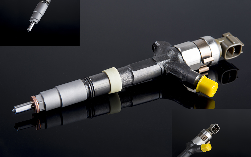 A fuel injector laying on a black background.