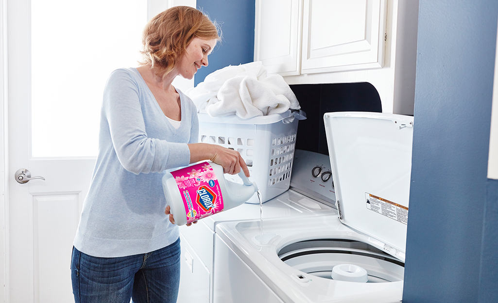 A woman adds bleach to a washing machine. 