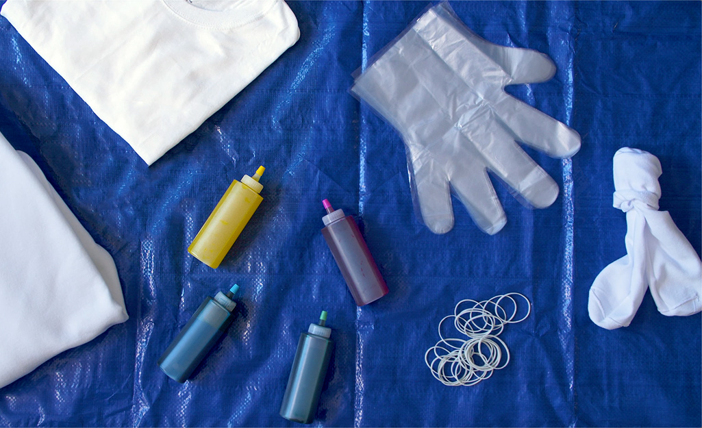 A shirt, tie-dye kit, gloves, socks and rubber bands displayed on a tarp.