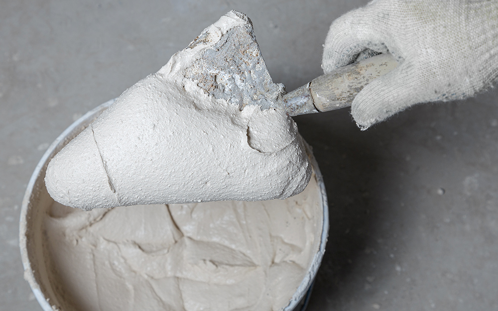 A person mixing thinset mortar to tile a shower.