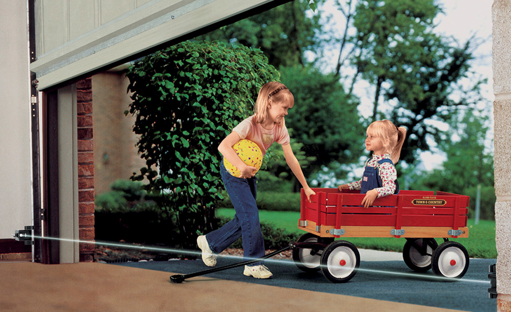 Two children activate a garage door safety sensor.