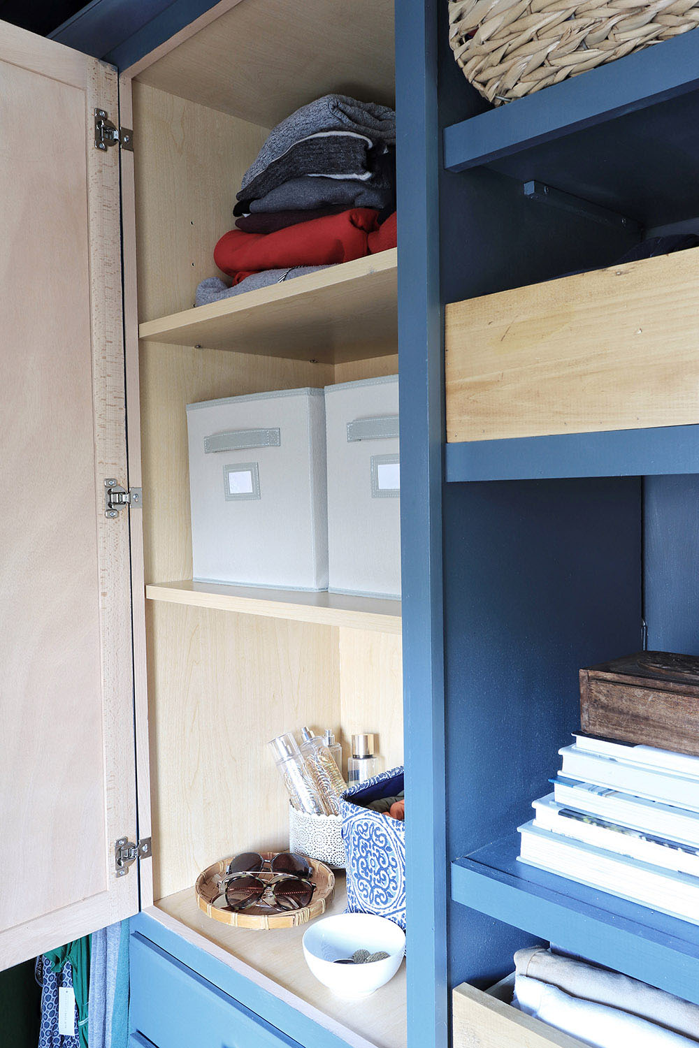 A closet cabinet open with shelves and storage bins