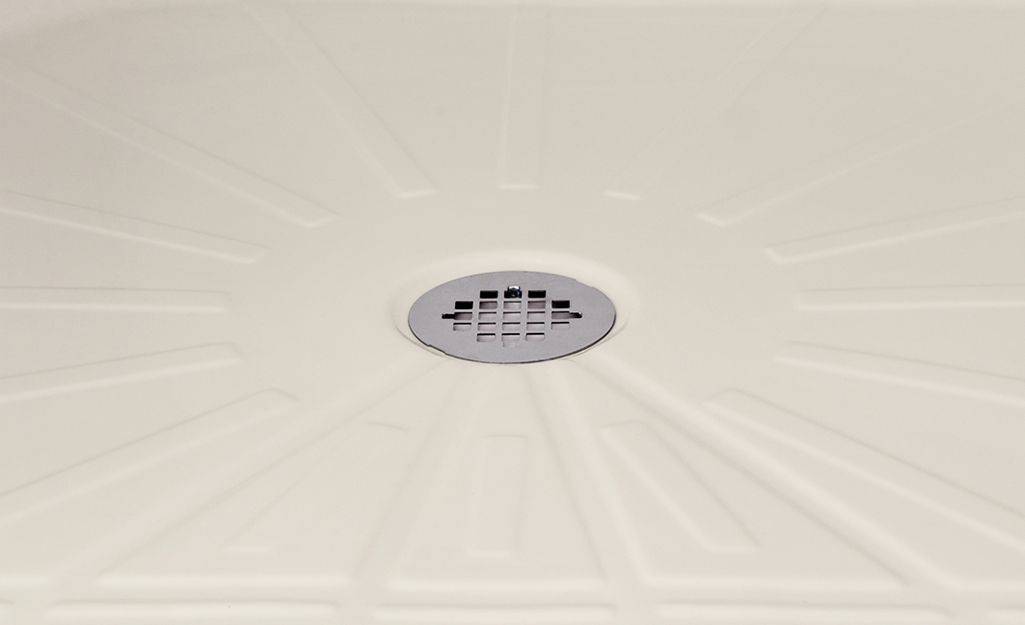 The clean floor of a shower surrounds a clear drain.