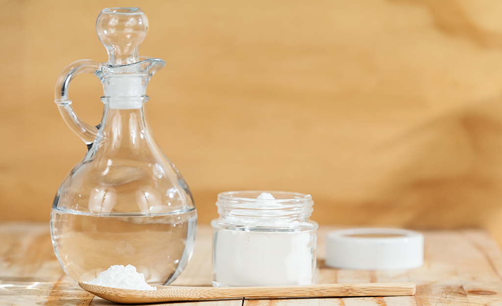 A cruet of vinegar and container of baking soda on a table.