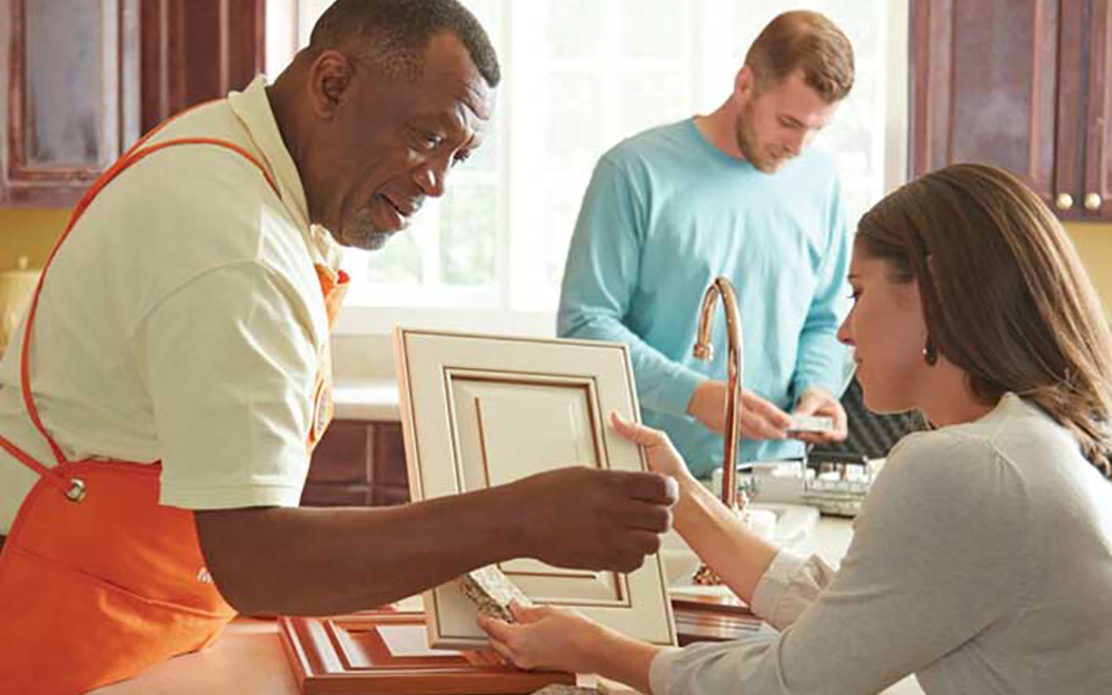 An expert from The Home Depot shows a customer how to update kitchen cabinets with refacing.