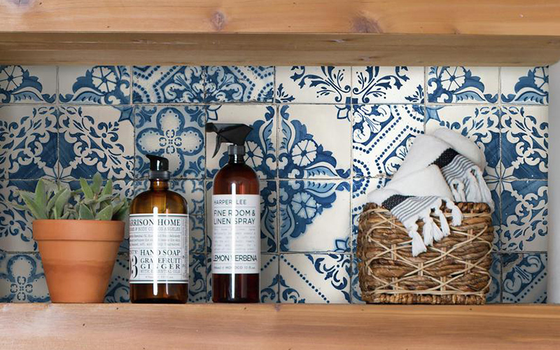 An inside kitchen shelf with a colorful wallpaper backing.