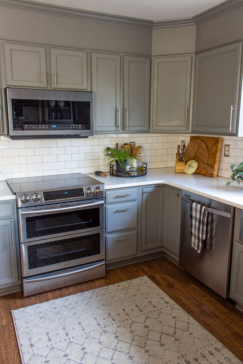 The corner of a kitchen with a new stainless steel microwave and double oven range.