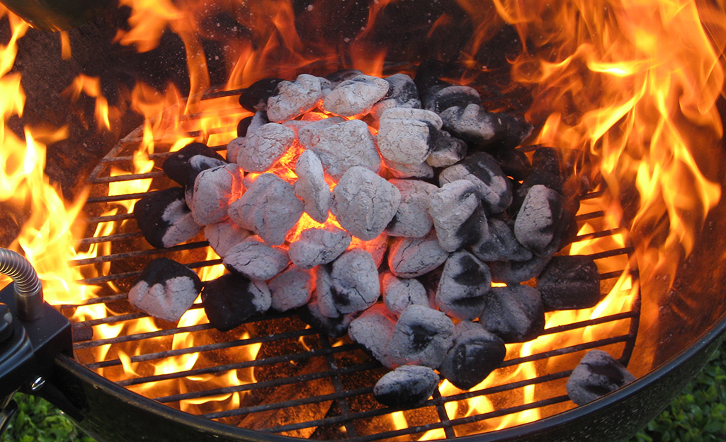 Charcoal briquettes burn on top of a grill.