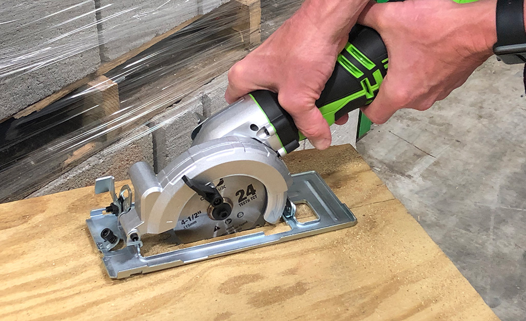 A person cutting plywood with a circular saw.