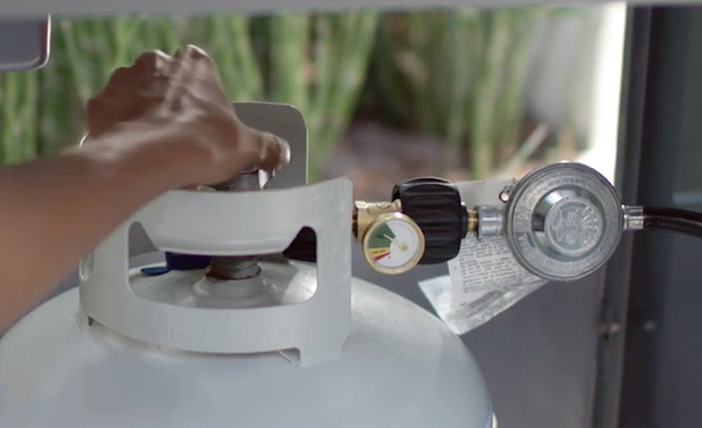 A person adjusting the valve on a propane tank.